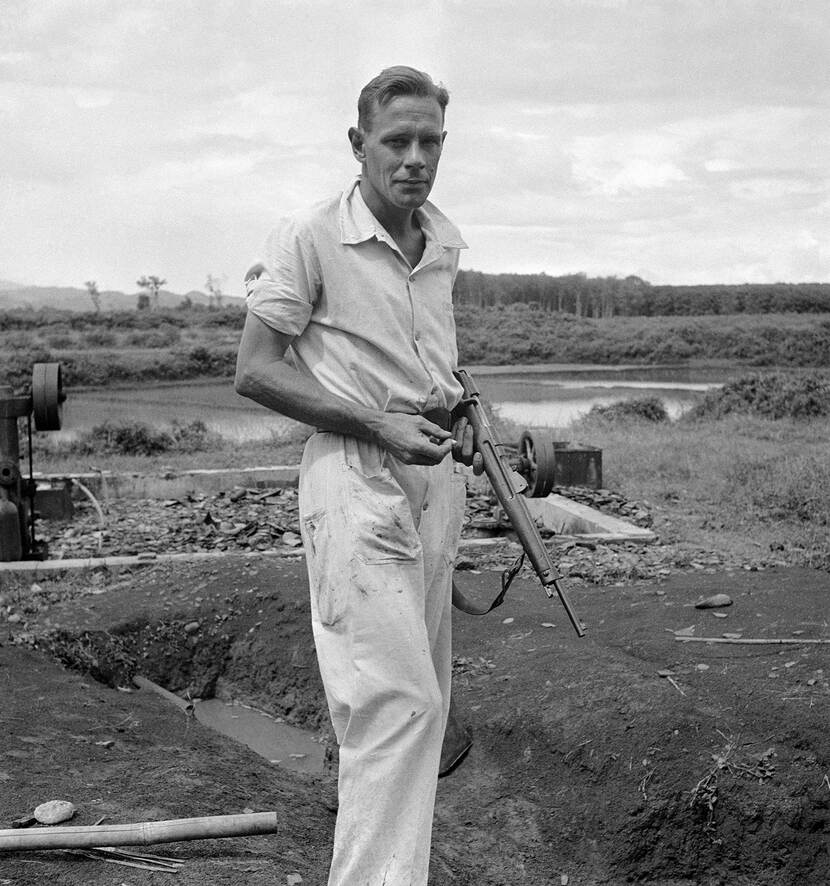 Foto door Cas Oorthuys (1908-1975), Bewapende Nederlandse rubberplanter poseert voor een pompinstallatie langs een rivier, Indonesië, 1947 © Cas Oorthuys / Nederlands Fotomuseum Object K88384